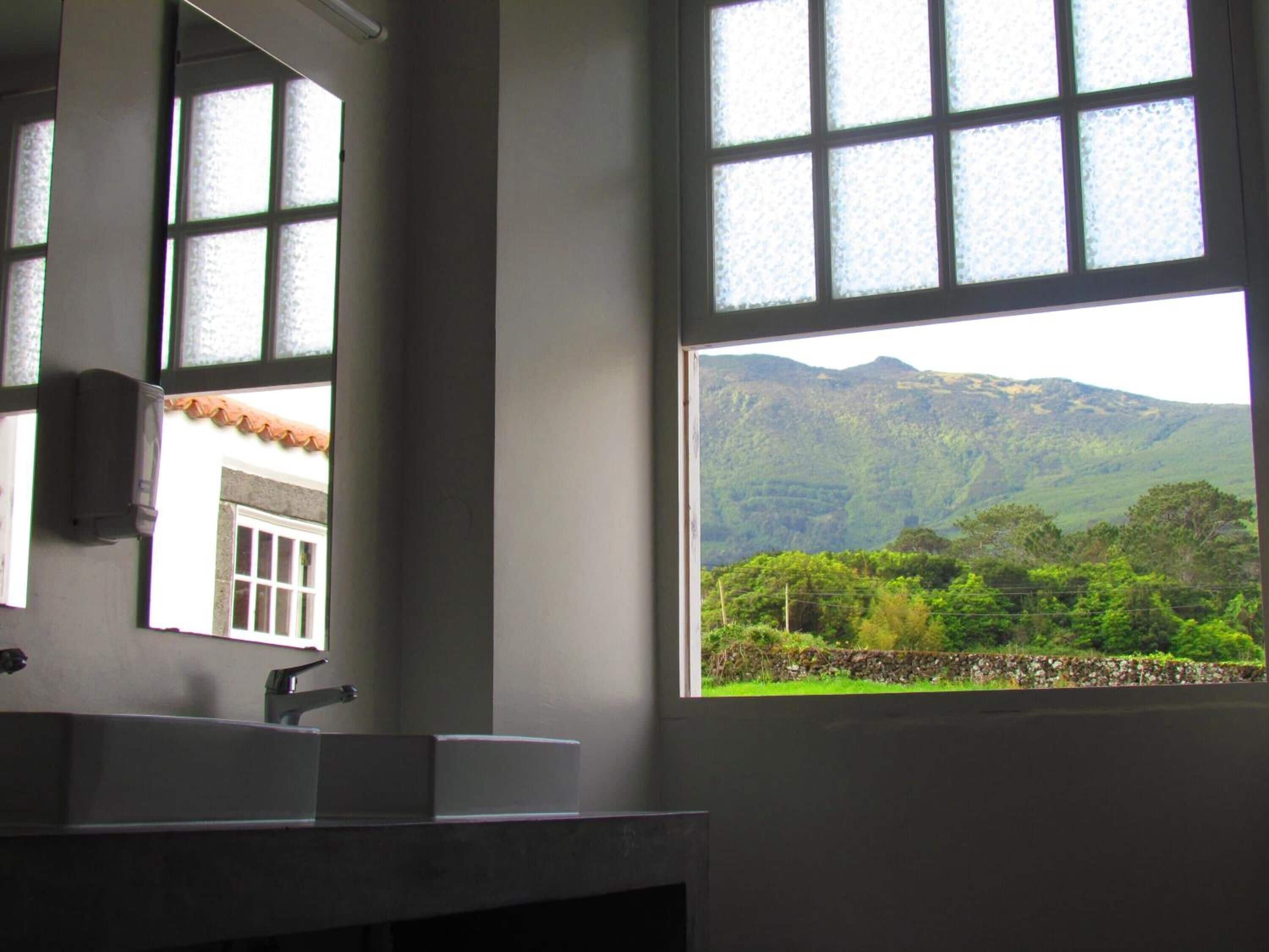 Un baño con un amplio ventanal que ofrece vistas a un paisaje montañoso.