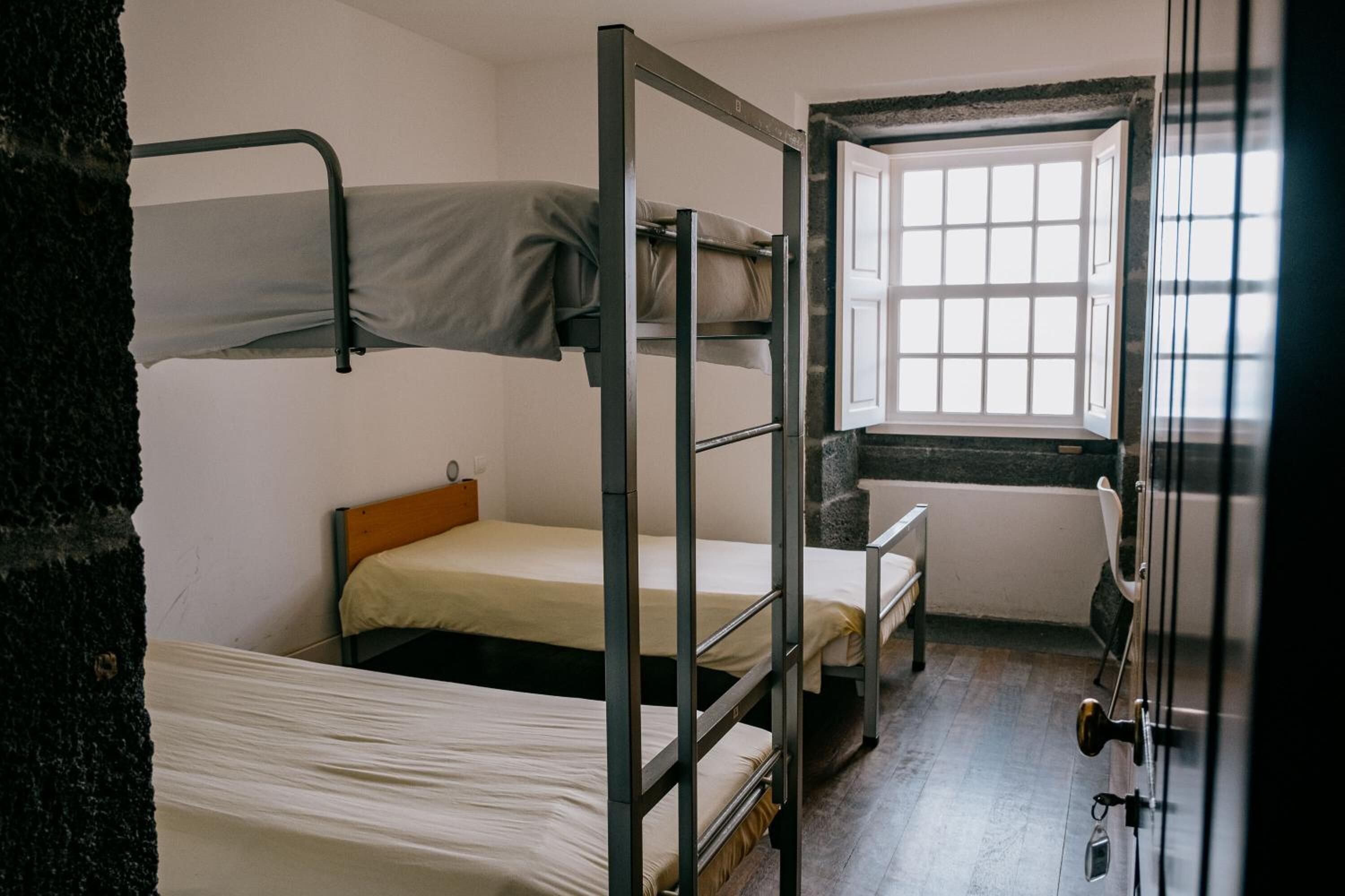 A bunk bed room with a window and a door.
