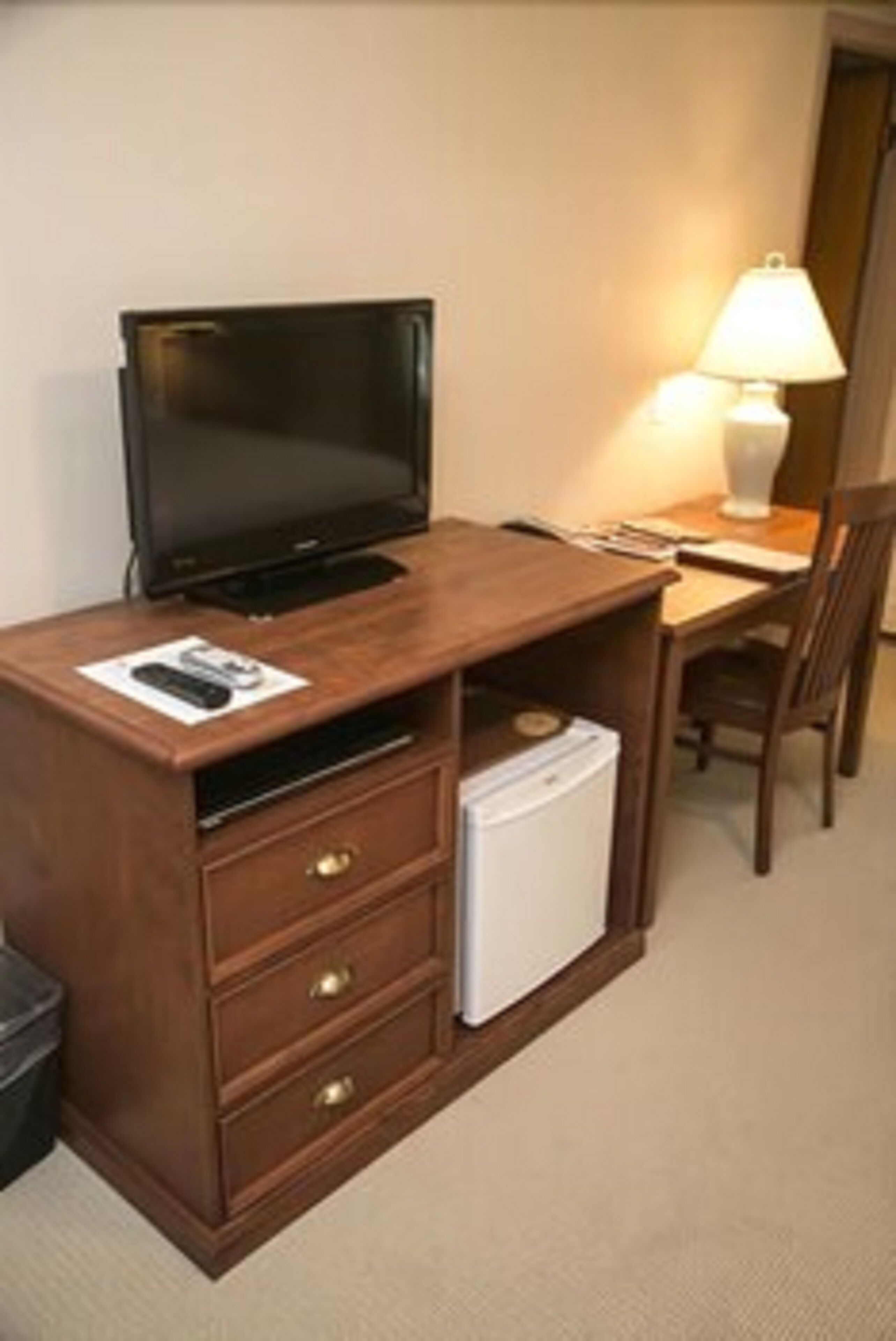 Ein Holztisch mit Fernseher, Lampe und Kühlschrank.