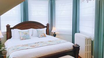 A neatly made bed with a floral bedspread, a wooden headboard, and a bedside lamp.