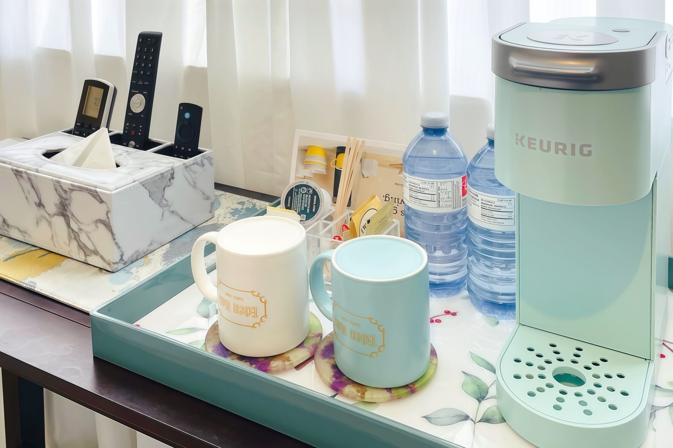 A kitchen counter with a marble organizer, two mugs, a Keurig coffee maker, a water bottle, and a tissue box.