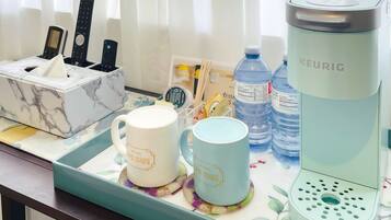 A kitchen counter with a marble organizer, two mugs, a Keurig coffee maker, a water bottle, and a tissue box.