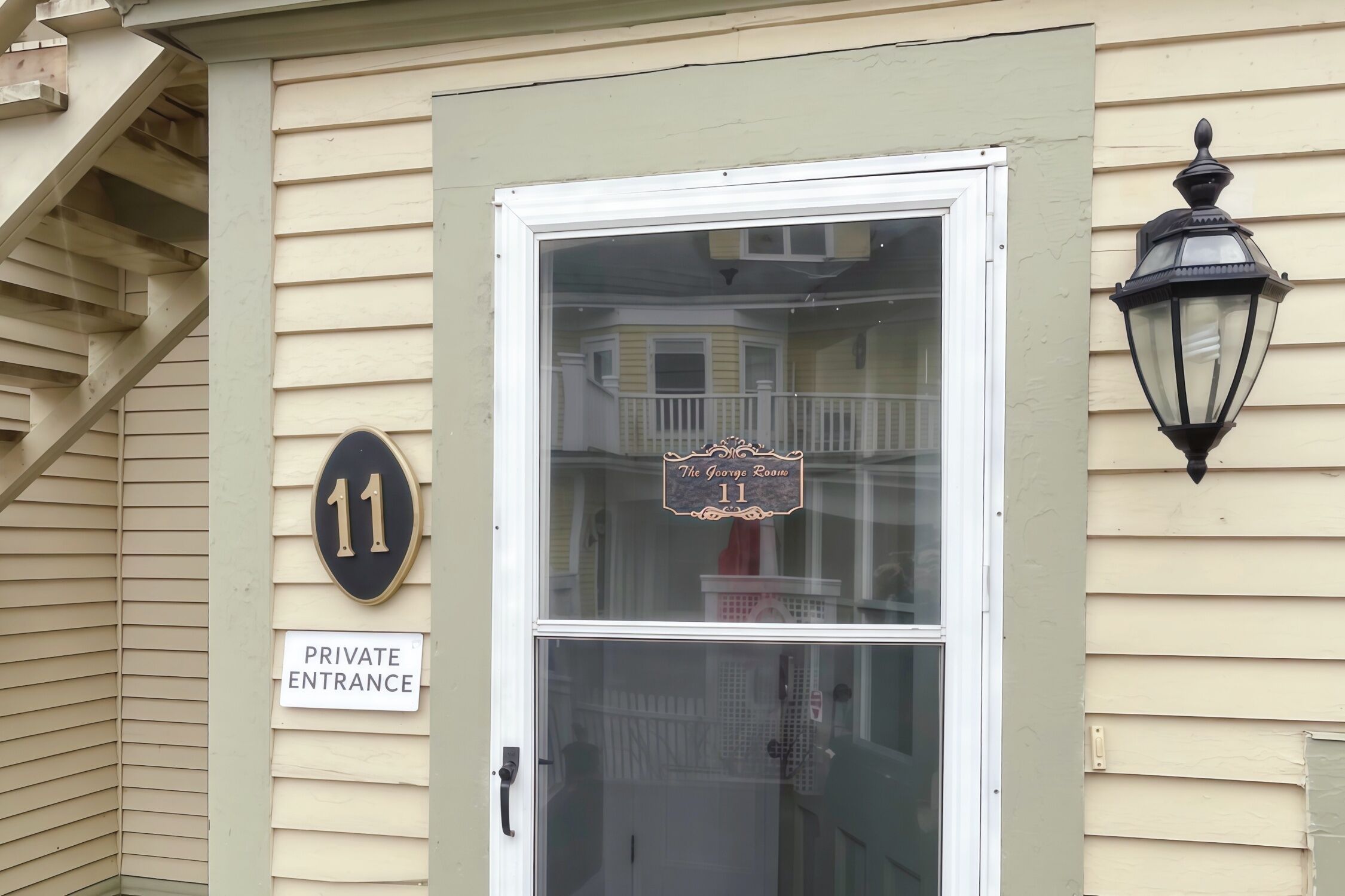A private entrance door with a number 11 sign, a glass door, and a black lantern on the wall.