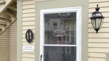 A private entrance door with a number 11 sign, a glass door, and a black lantern on the wall.