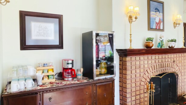 Un vestíbulo de hotel con chimenea de ladrillo, una estación de café, obras de arte enmarcadas y apliques de pared.