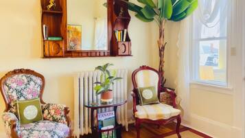 Una habitación acogedora con dos sillones, un espejo, un radiador y una ventana con cortinas.