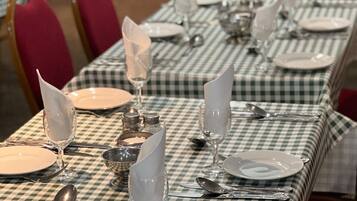 A dining area with checkered tablecloths, neatly set tables with plates, glasses, and cutlery.