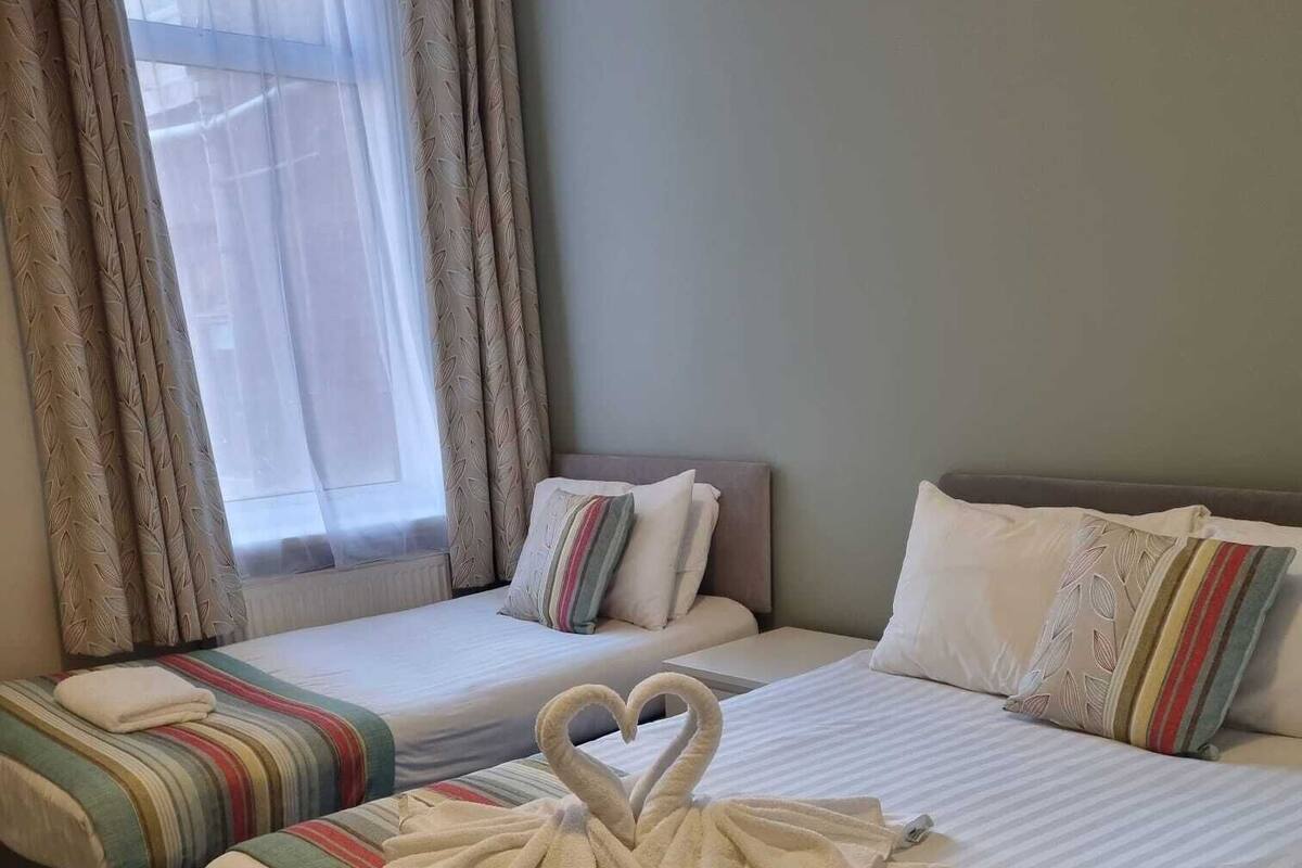 A hotel room with two beds, each with striped bedding and pillows.