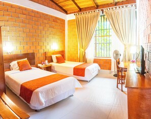 A hotel room with two beds, a wooden ceiling, brick walls, a window with curtains, a desk with a lamp, and a TV. -  Altavista Casahotel - Asociado Casa Andina (Moyobamba)