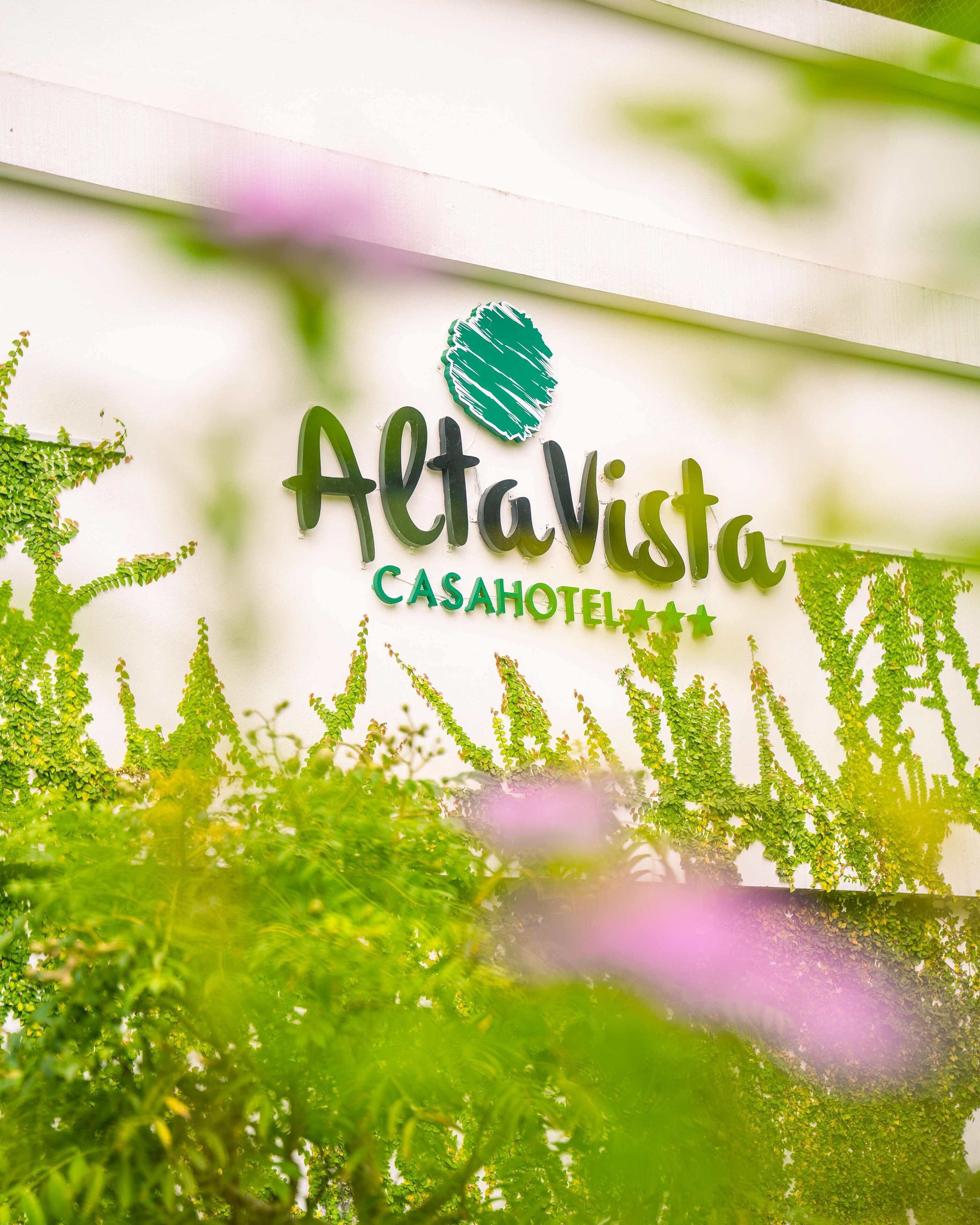 Letrero de AltaVista CASAHOTEL con logotipo verde y follaje decorativo.