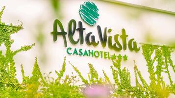 Letrero de AltaVista CASAHOTEL con logotipo verde y follaje decorativo.
