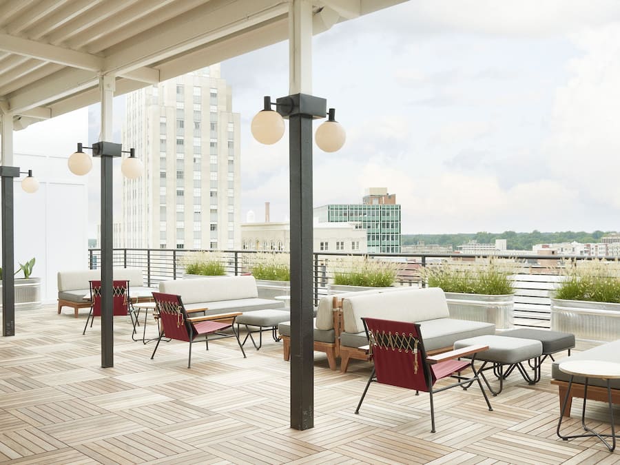 A rooftop terrace with outdoor seating, potted plants, and a city view.