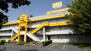 Un hôtel à la façade jaune et blanche, doté d’un escalier imposant et d’une enseigne indiquant qu’il s’agit d’un hôtel « Première Classe ».