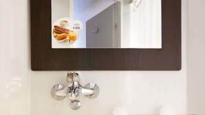 Une salle de bain avec un lavabo blanc, un miroir et un robinet.