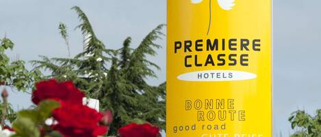 Un letrero amarillo con el texto 'PREMIERE CLASSE HOTELS' y traducciones en varios idiomas.