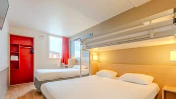 A hotel room with two beds, a red wardrobe, a window with a view, and a bunk bed.