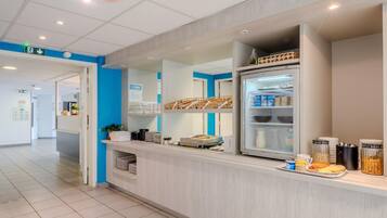 A hotel reception area with a counter, a refrigerator stocked with food, and a blue wall.