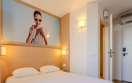 A hotel room with a bed, a wall-mounted mirror, and two bedside lamps.