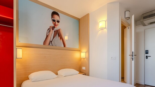 Una habitación de hotel con una cama, un espejo en la pared y dos lámparas de noche.