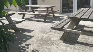 Un patio al aire libre con mesas de picnic y un edificio con ventanas grandes y una puerta.