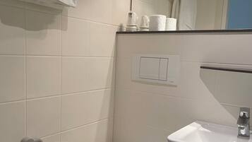 A bathroom with a toilet, a sink, and a towel hanging on the wall.
