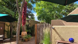 A courtyard with a seating area, a large potted plant, and a hanging red chili pepper. - Casa de Tres Lunas (Santa Fe)