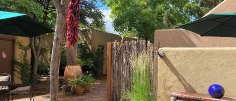 A courtyard with a seating area, a large potted plant, and a hanging red chili pepper.