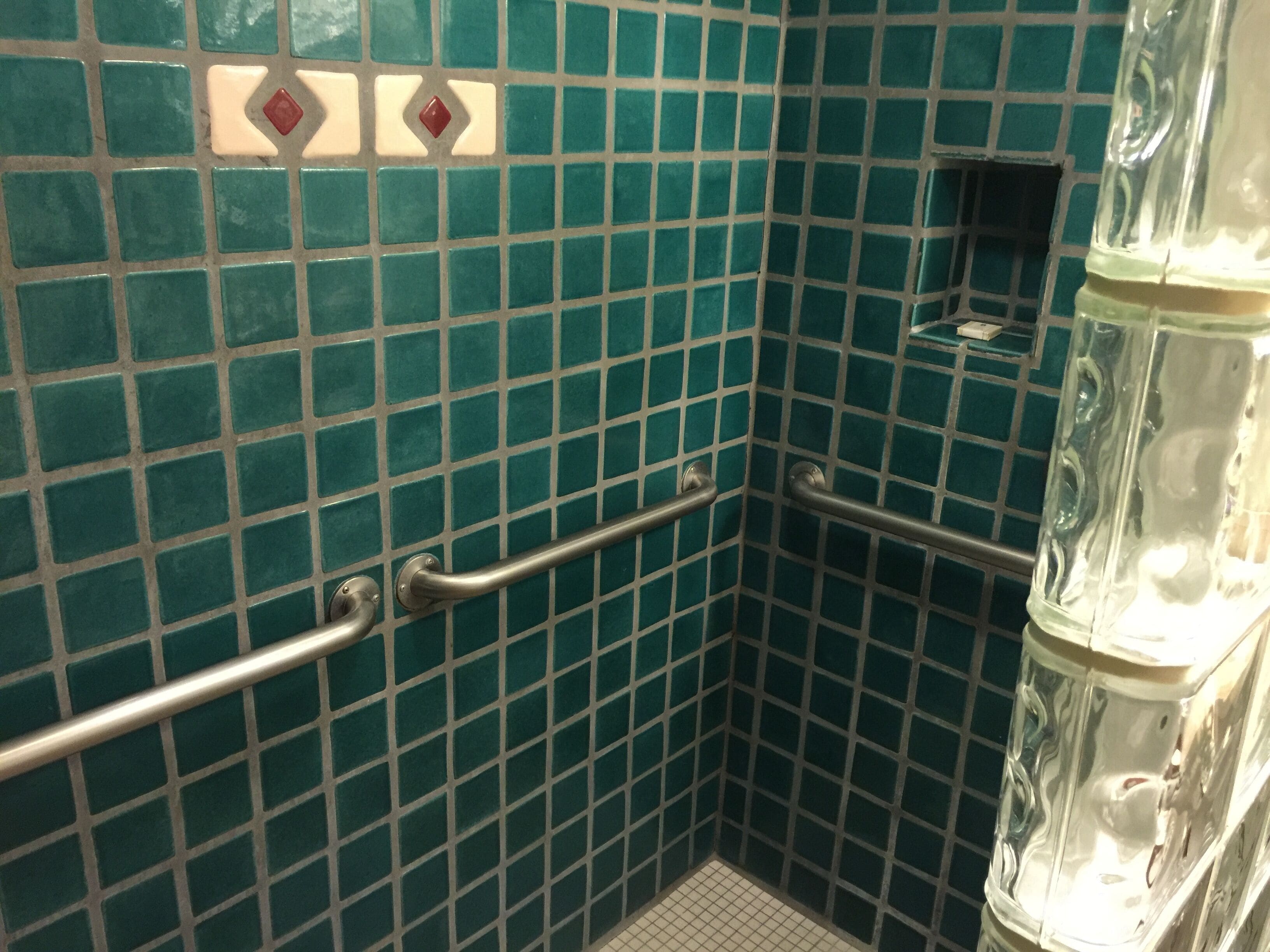 Un baño con azulejos, barandilla y cabina de ducha de vidrio.