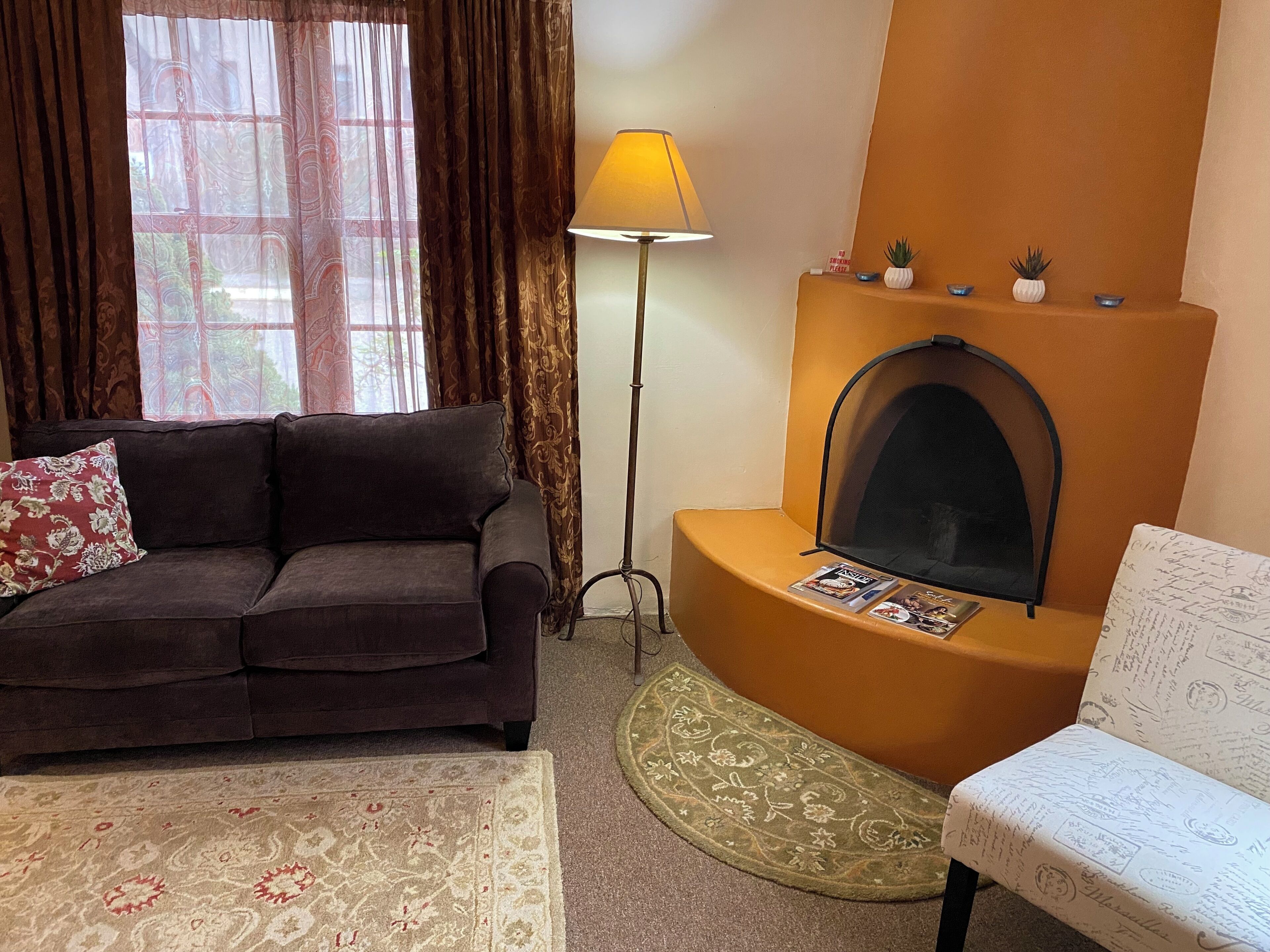 A living room with a sofa, a floor lamp, a fireplace, and a small table with magazines.