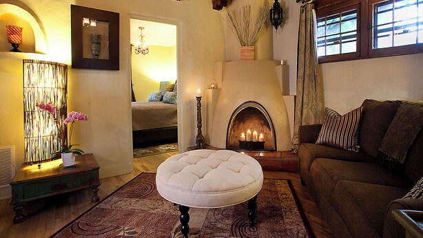 A cozy living room with a fireplace, a sofa, and a decorative ottoman. - Casa de Tres Lunas (Santa Fe)