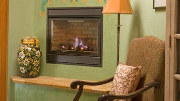 A cozy room with a fireplace, a chair with a patterned cushion, and decorative vases.