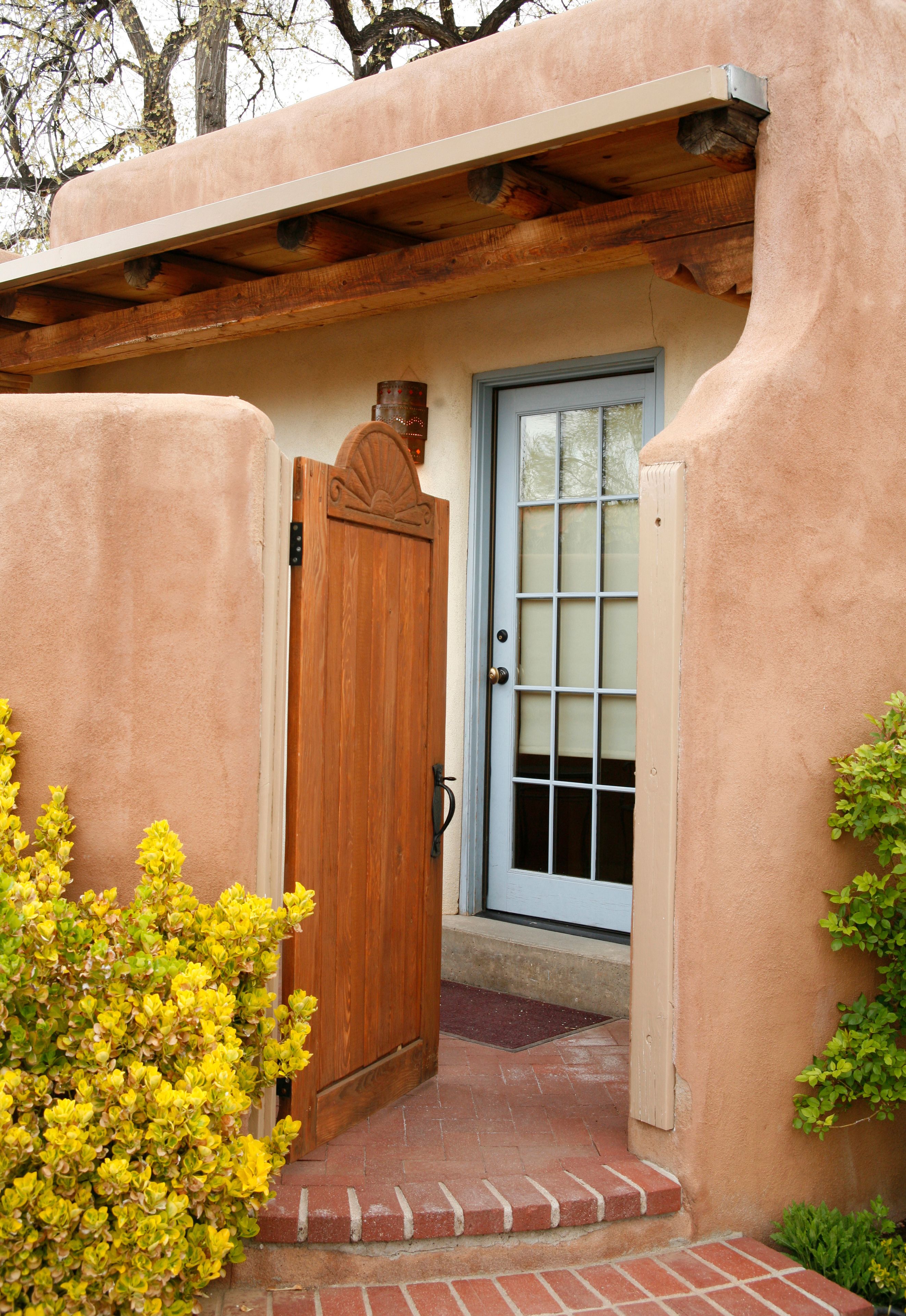 A stucco building with a wooden door and a window with a grid pattern.