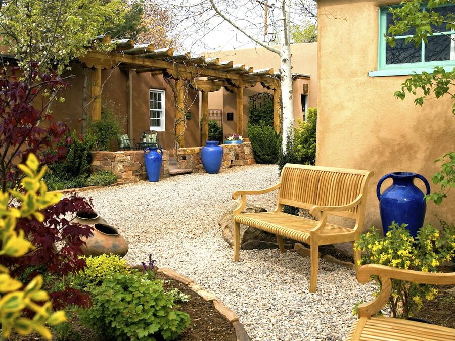 A patio with a wooden bench, two large blue vases, and a pergola.