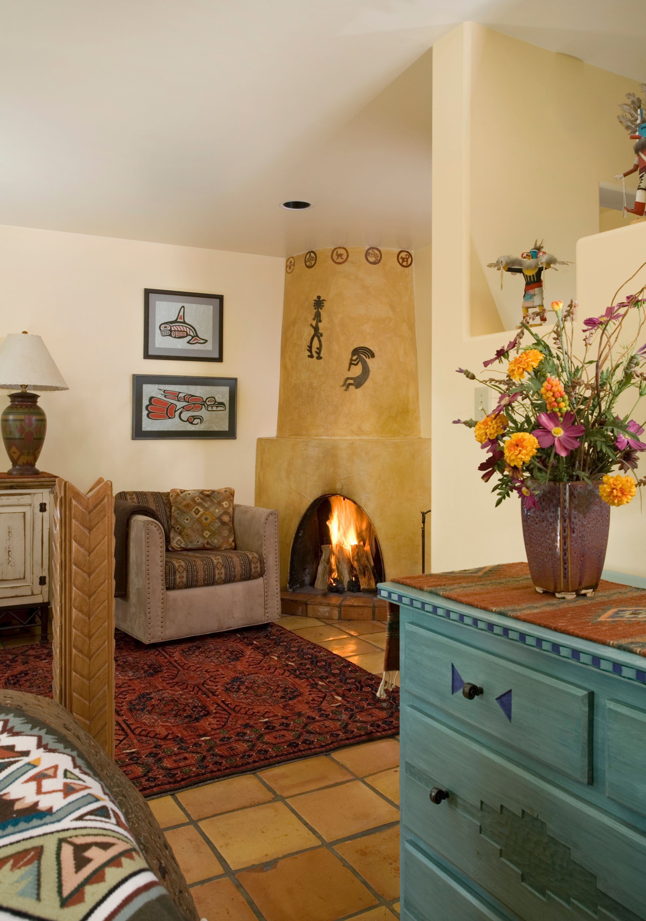 Een woonkamer met een bank, een open haard, een decoratieve vaas met bloemen en een kamerbreed tapijt.