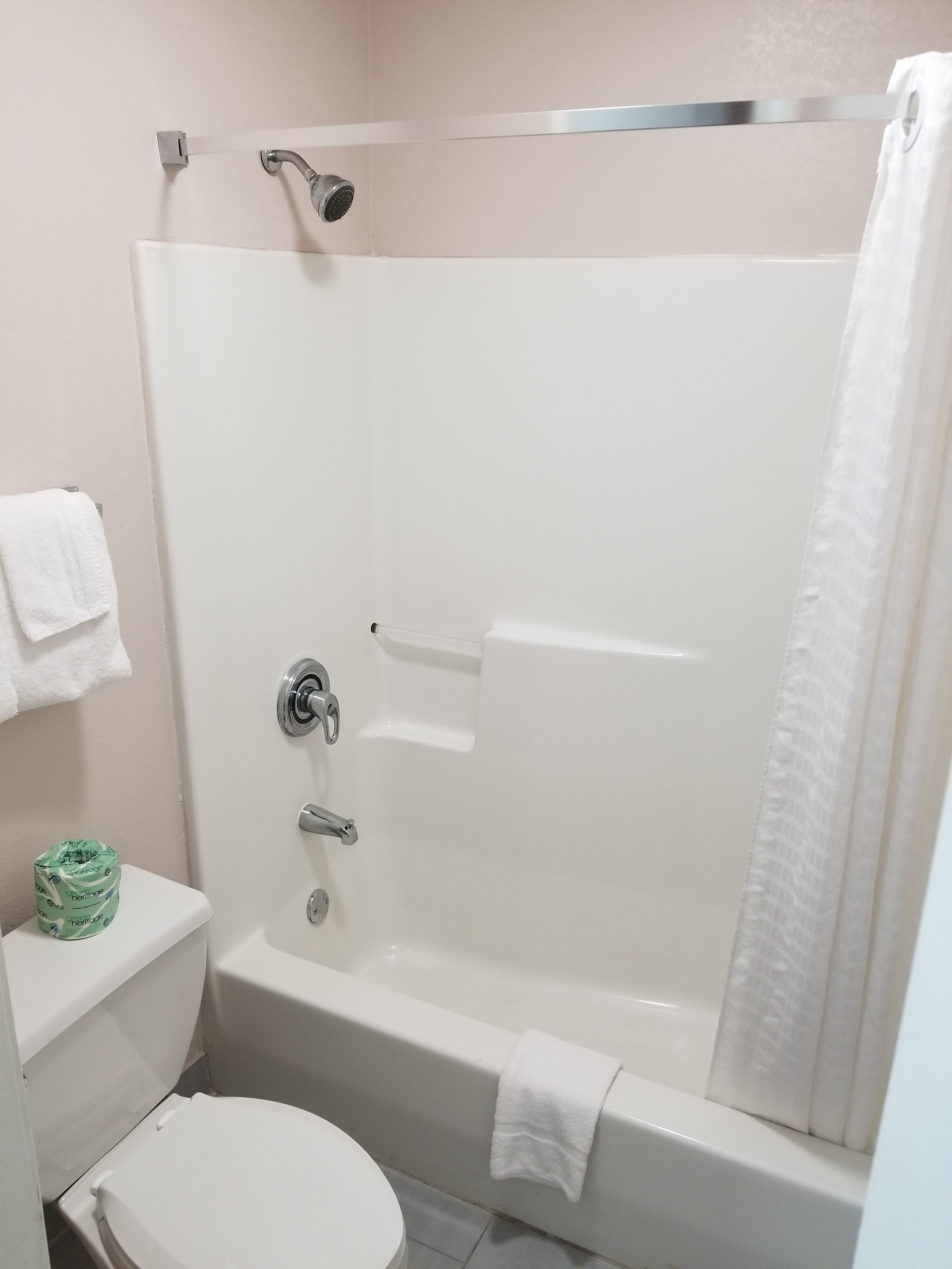 Une salle de bain avec une douche, des toilettes et un porte-serviettes.