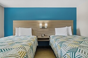 A hotel room with two beds, a wooden headboard, bedside lamps, and a phone on the nightstand.