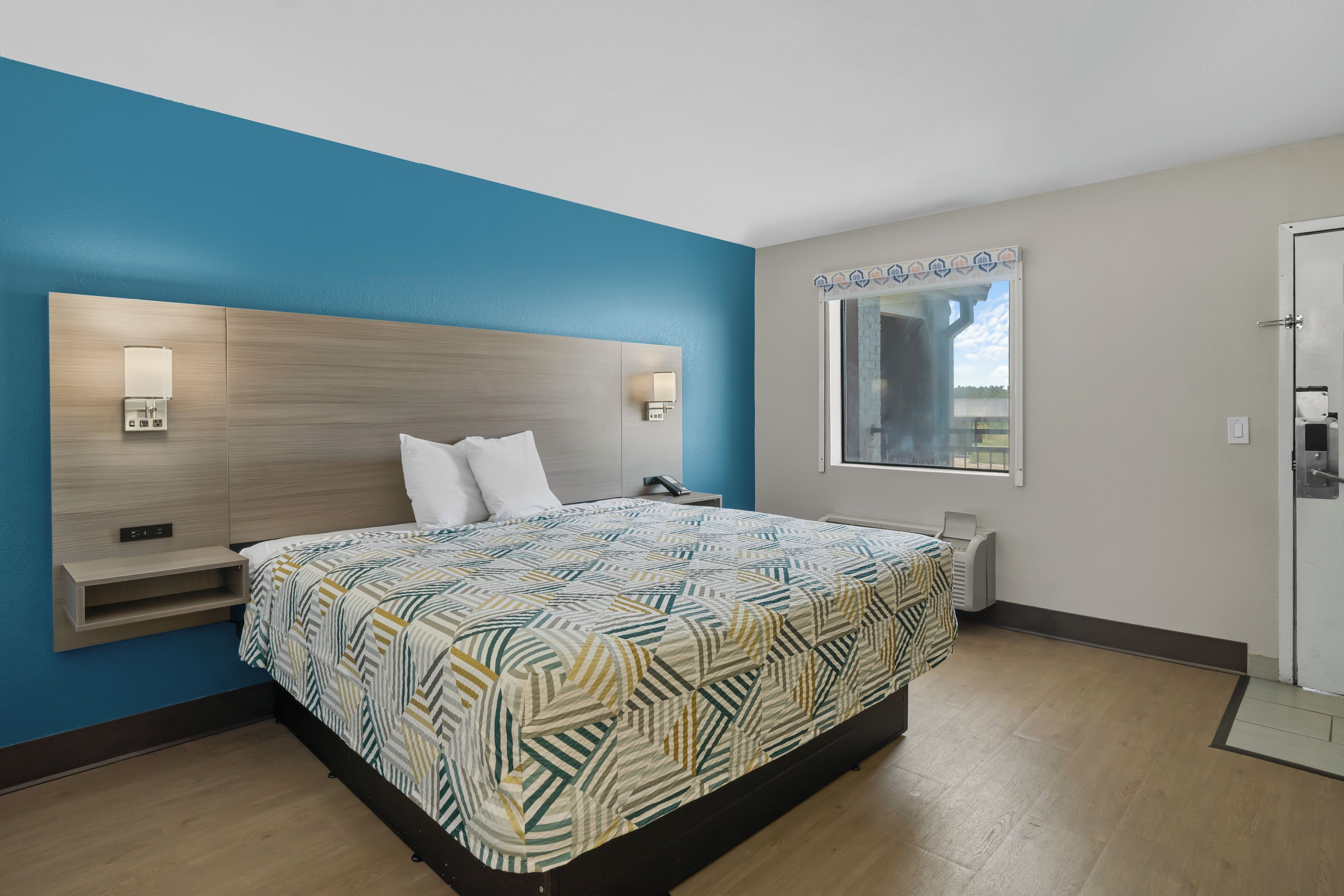 Une chambre moderne avec un grand lit, des lampes de chevet, une étagère intégrée et une fenêtre donnant sur un beau paysage.