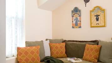 A cozy room with a built-in bench, a patterned rug, and two wall-mounted religious icons.