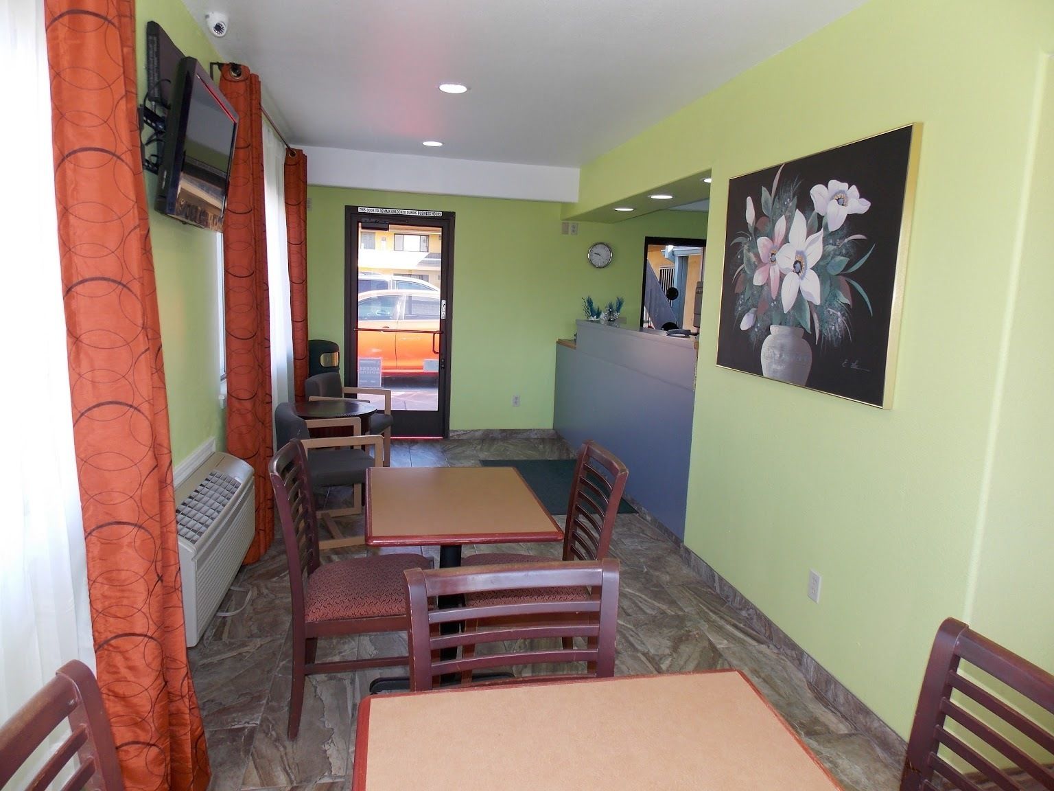 Un comedor con mesas y sillas, un cuadro en la pared y vistas al exterior a través de un ventanal.