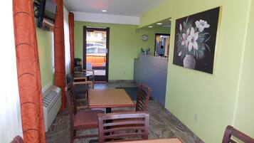 Un comedor con mesas y sillas, un cuadro en la pared y vistas al exterior a través de un ventanal.