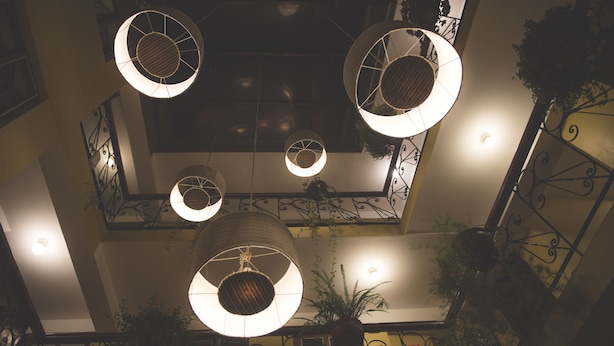 Um átrio de vários níveis com luminárias circulares penduradas e grades de ferro forjado.