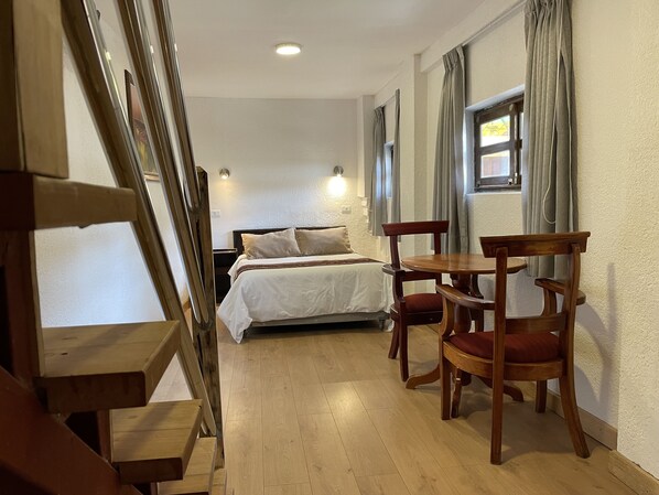 A bedroom with a bed, bedside table, and a small wooden table with chairs. - Hotel Oblitas Plaza De Armas Cusco (Cusco)