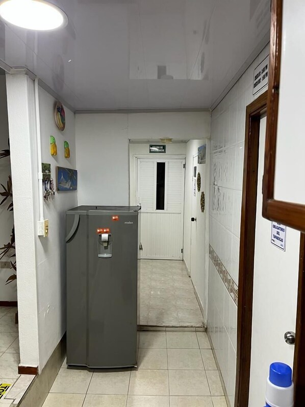 A hallway with a water dispenser, a door labeled "Sala de Emergencia," and a sign indicating "Obligatorio del Tapas." - Posada Caribbean Refuge (San Andrés)