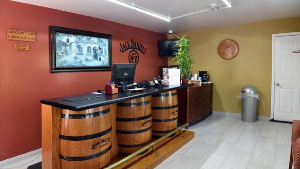 A reception desk with wooden barrels, a computer, a clock, and a television on the wall. - Lynchburg Country Inn (Lynchburg)