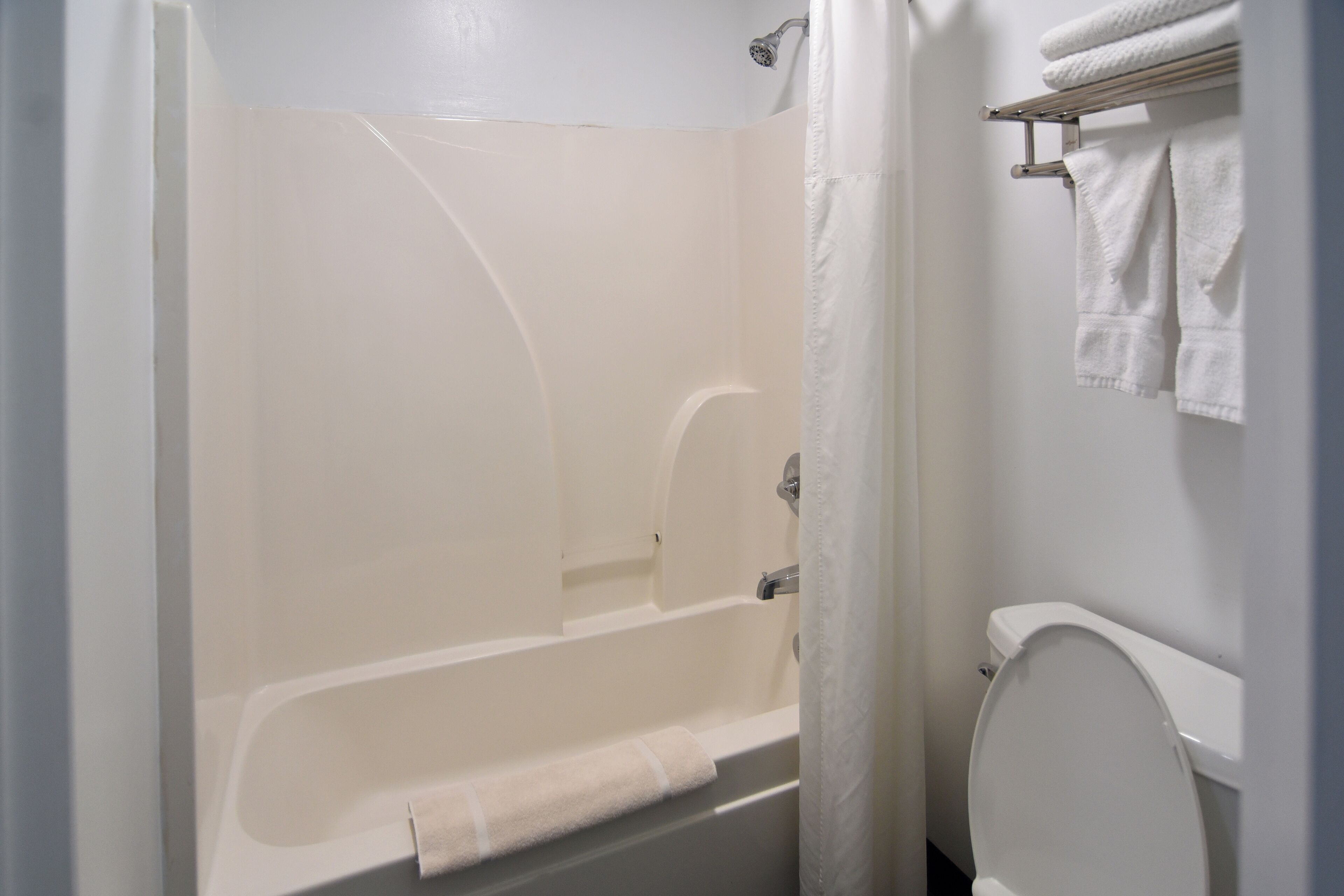 A bathroom with a bathtub, toilet, and towel rack.