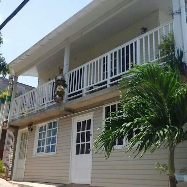 A two-story building with a balcony, a door, and a window. - Posada Nativa Atardecer Isleno (San Andrés)