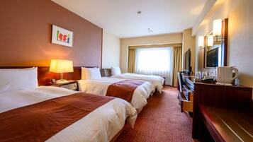 A hotel room with two beds, a desk, a television, and a window with curtains.