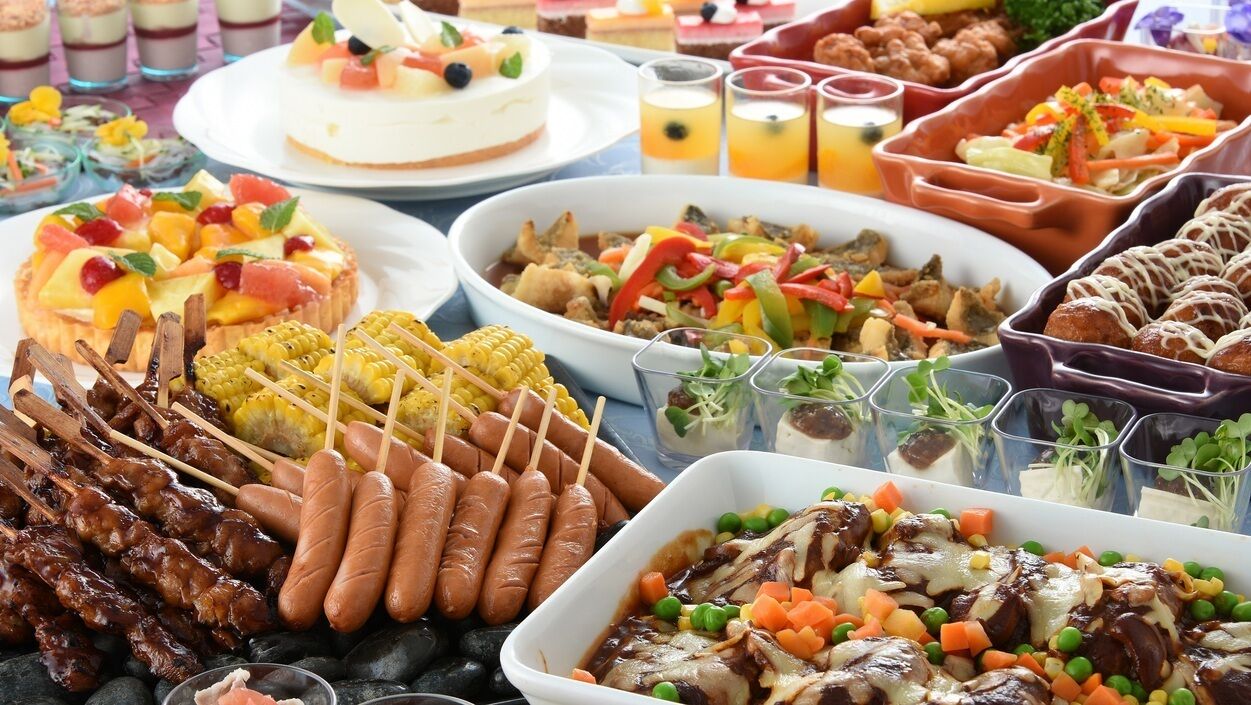 A buffet with various dishes including skewers, sausages, and a variety of salads and meats.