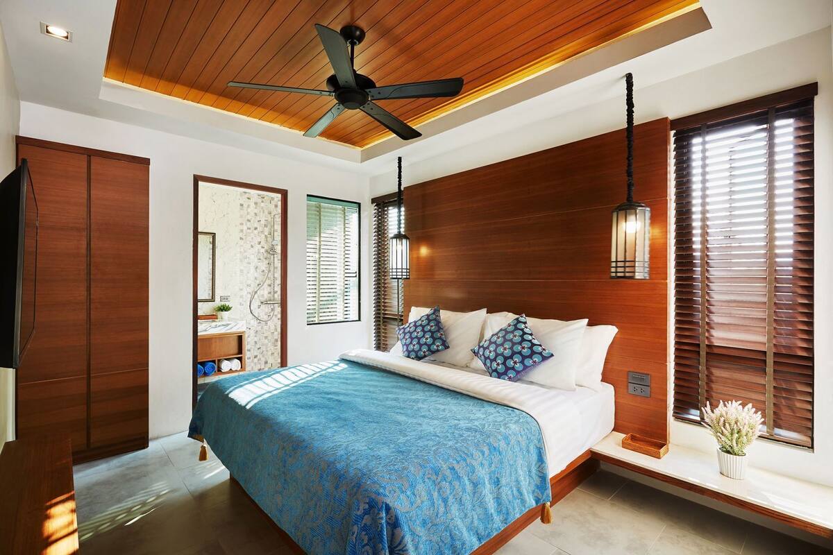 Ein Schlafzimmer mit Bett, Holzboden und Deckenventilator.