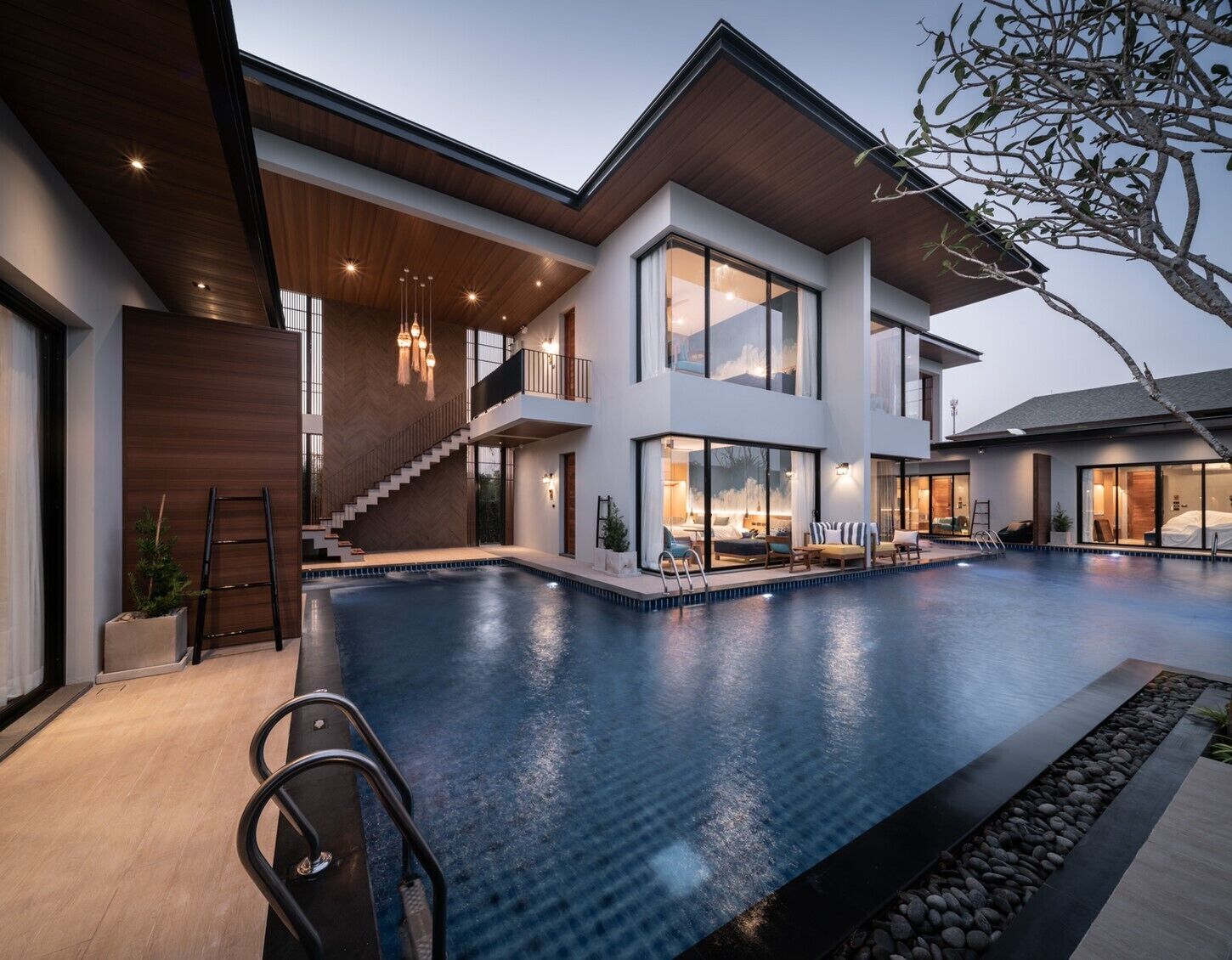 A modern two-story house with a large swimming pool, a staircase, and a balcony.
